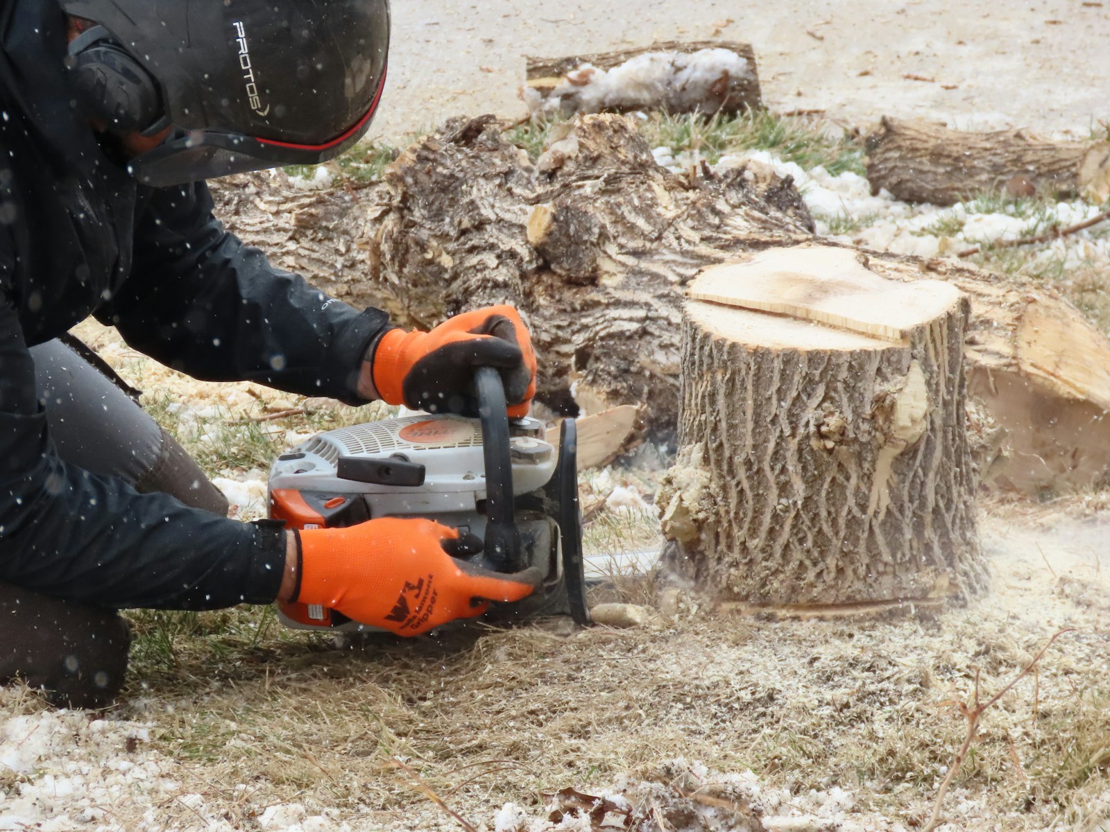 man in black jacket and blue denim jeans holding orange and black power tool